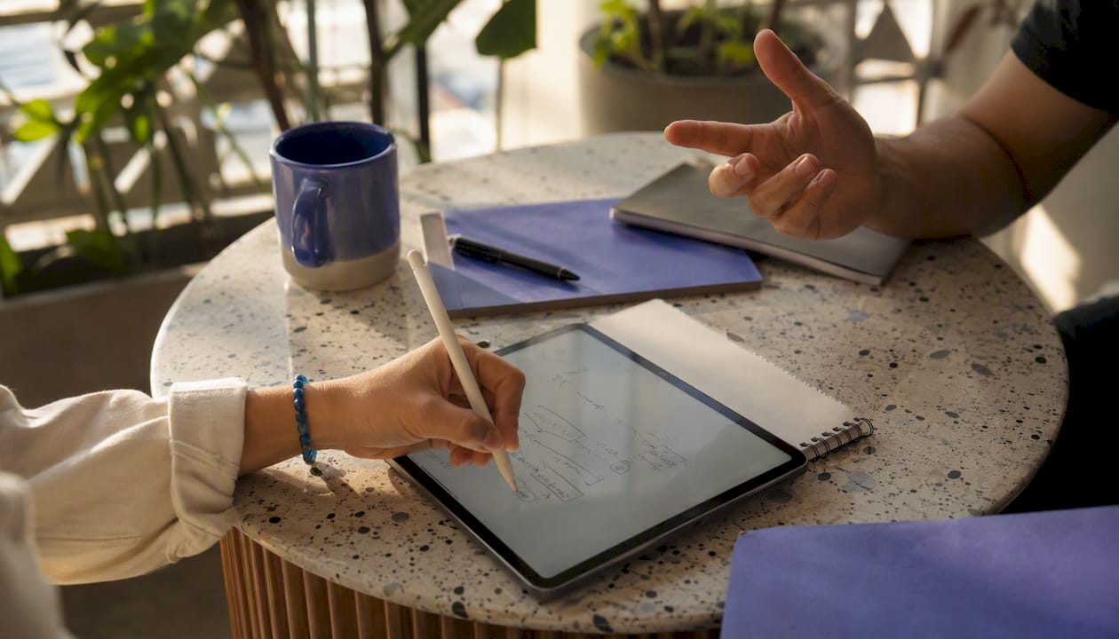 Hands writing AI code on digital tablet
