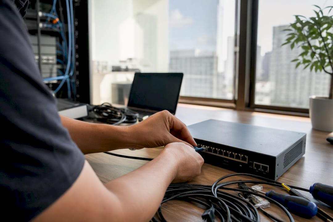 Hands connecting network hardware in tech workspace