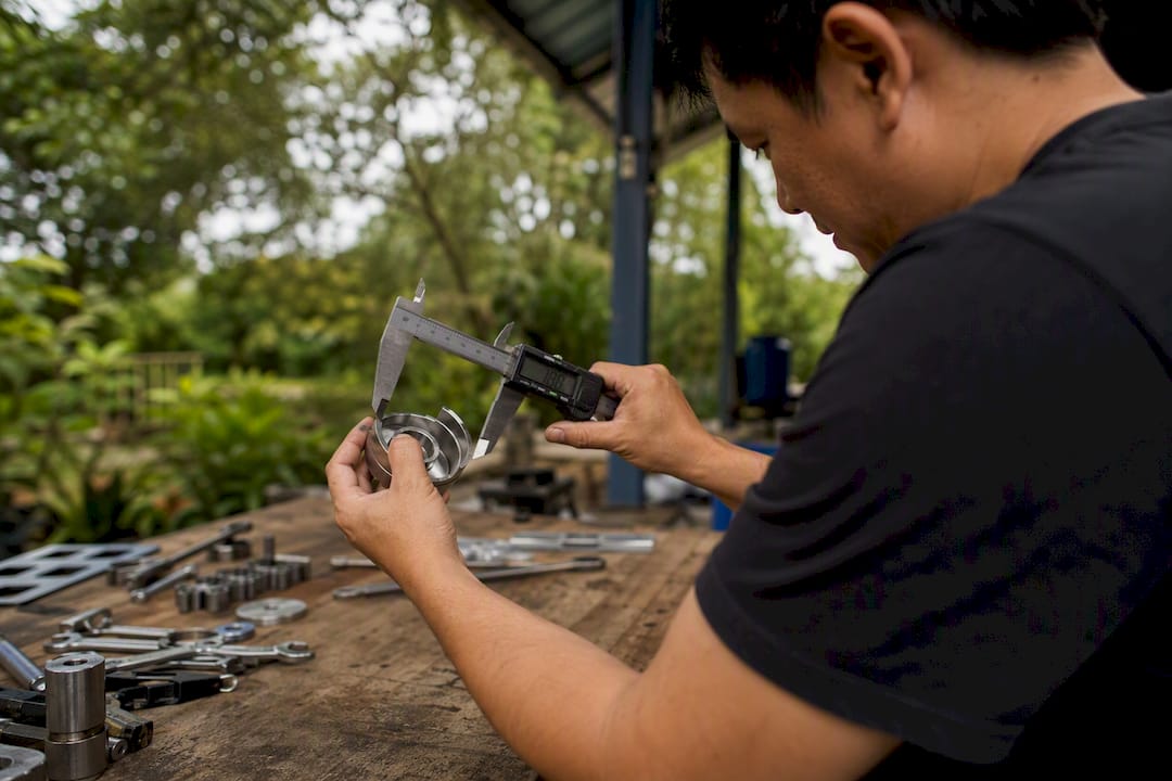 Technician measuring machined part with calipers