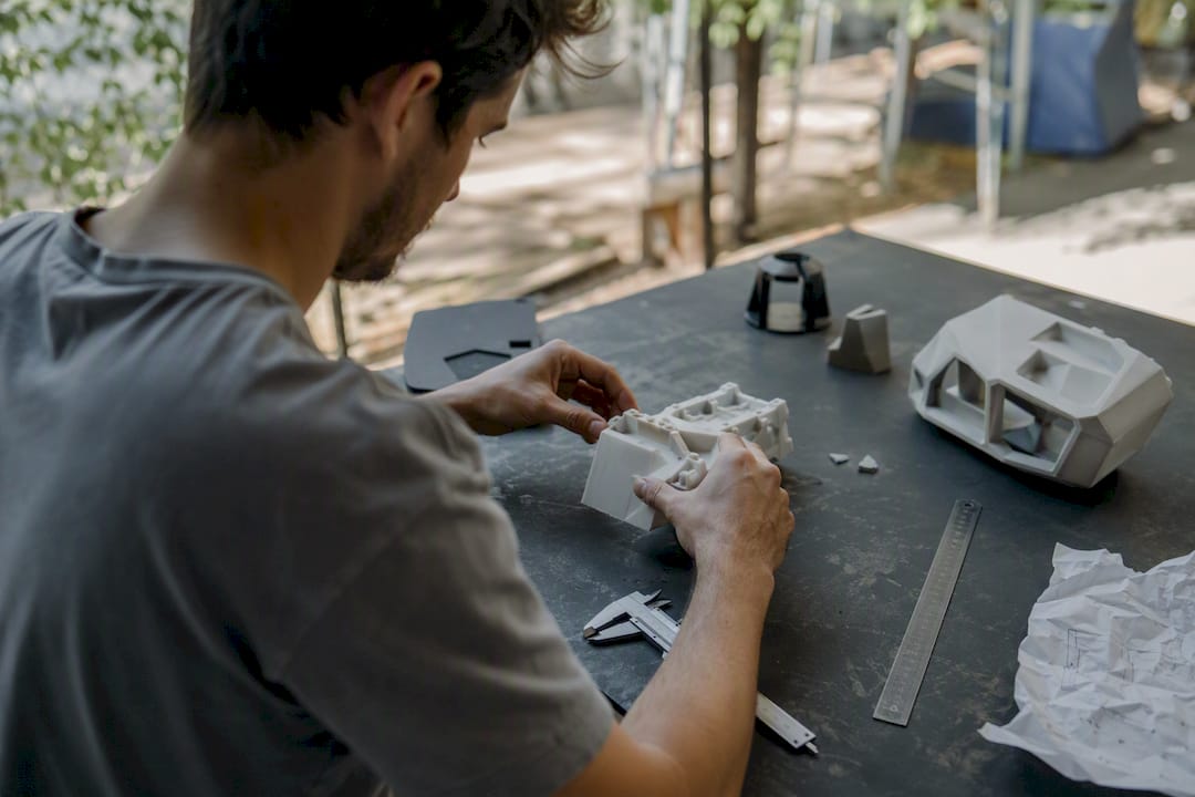 Hands adjusting a prototype model on drafting table